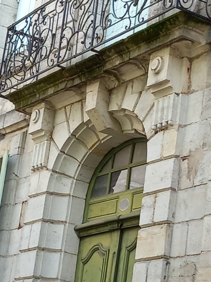 Über einer hohen Tür unter einem Fenster sind zwei Runde Verzierungen,  die an Augen erinnern und eine längsförmige, die eine Nase darstellen könnte.