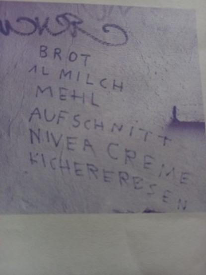 Foto eines Graffiti an einer Hauswand: Brot, 1l Milch, Mehl, Aufschnitt, Nivea Creme, Kicherbsen