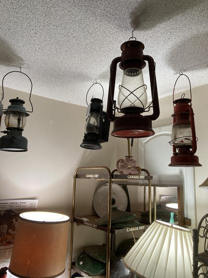 Several photos of stuff in side the shop. The pictures show handing kerosene lamps, old toys, stone crockware, and decorative metal cookie  tea tins, lamps and more.
