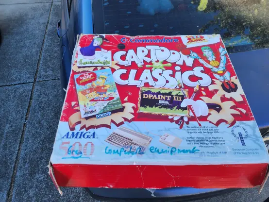 A beaten up box for an Amiga 500, sitting on the back of a car