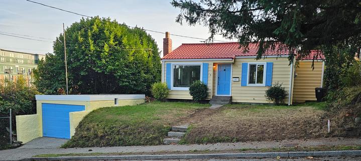 A small house, which was a rental, used to be a bedraggled white, with a ratty yard, and now has been spiffed up. The lawn is trimmed, the hardscape cleaned up. The house is now a pale sun yellow, with vivid sky blue and trim and a blue door. The roof is freshly cleaned pink tile. The below ground level garage off to the left is also yellow with a blue door. There are trees on each side of the lawn. I would not be surprised if the house was be placed on the market soon.