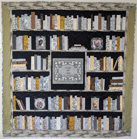 A large, bed-sized quilt for a couple who got married. It was designed to look like a bookcase, and includes "framed" photos of their dogs on some of the shelves. There is a central medallion with a fancy frame, and the names of the couple and their wedding date. There is also a "greenery" background on the sides of the bookcase, which the bride said was one of her favorite things.