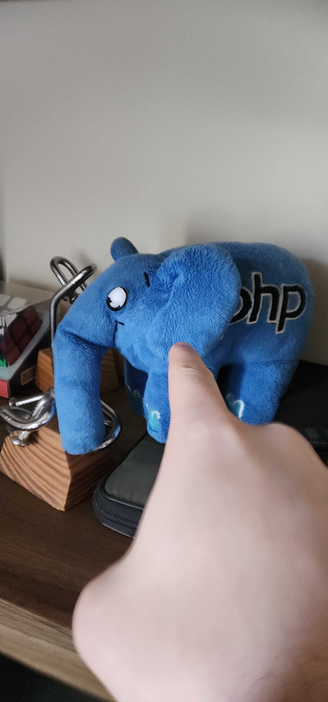 photo of my right hand pointing at a php elephant plush sitting among a collection of puzzles