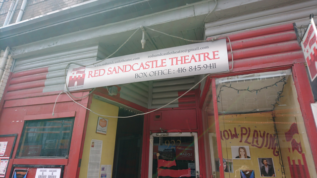 the outer facade of the charming red sandcastle theatre with it's sign saying box office and tel 416 845-9411 and their website redsandcastlethatre.com and email redsandcastletheatre@gmail.com