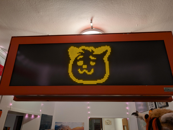 LED passenger information display showing a neofox woozy emoji