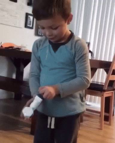 GIF: a young boy excitedly loads up a toy gun, points it at his dick, and fires. His joy immediately turns to regret.