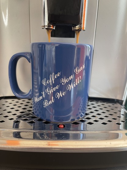 Coffee being poured into a blue cup. The cup has a slogan on it: „Coffee won’t give you gas, but we will!“