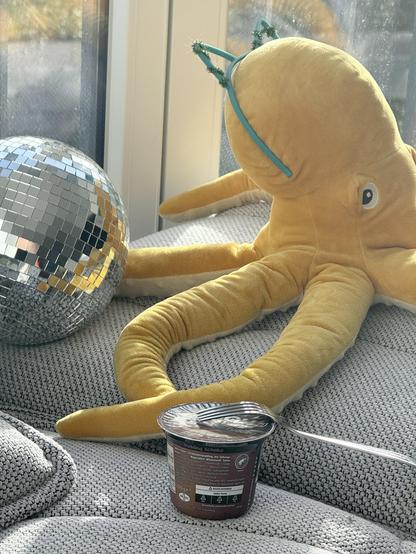 Artsy photograph of a fork lying on a cup of pudding (with a plush octopus in rye background)