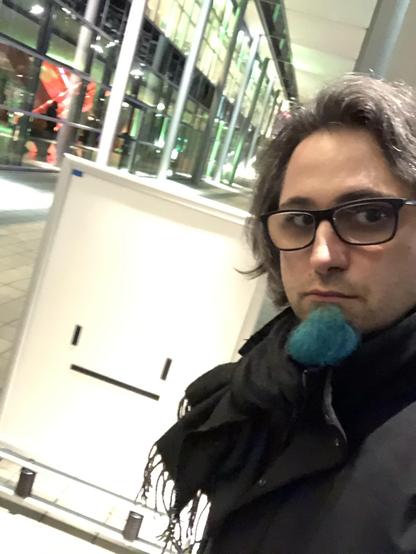 Selfie with a neutral face in front of a poster showing a neutral face emoji 