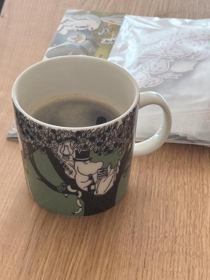 A coffee cup with Moomins on it. In the background, we can diffusely see some TelemetryDeck stickers 