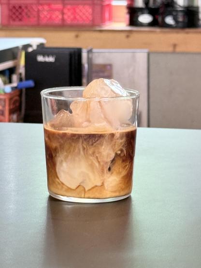A glass with swirls of coffee and oatmilk and lots of ice cubes 