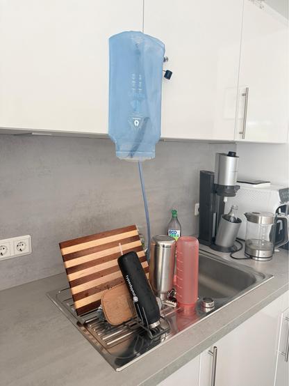 Kitchen photo. A blue drinking pouch for use in a backpack is drying and looks like an infusion 