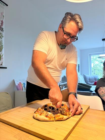Daniel cutting a pizza