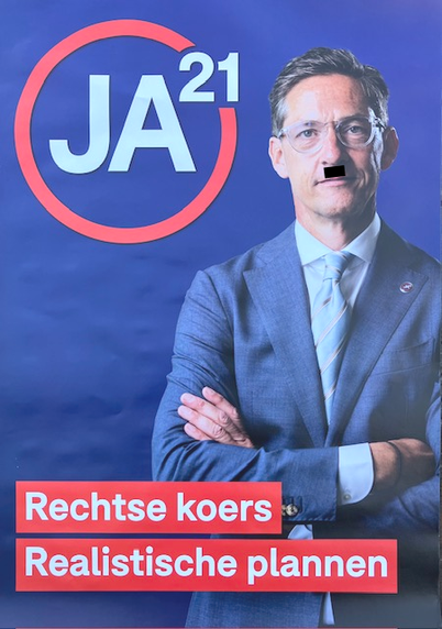 Verkiezingsposter van JA21 met een foto van politiek slettebakje Eerdmans. Op zijn bovenlip is een veelbetekenend zwart vlakje toegevoegd. 
