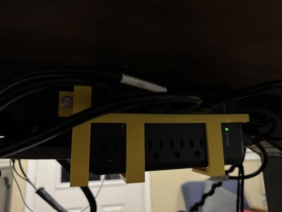 A photo of a yellow harness, 3-D printed to hold a electrical strip