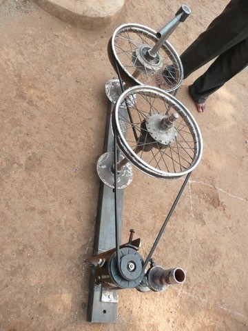 The cow power charging prototype. Motorcycle wheels using v-belts as reduction gear, driving a generator that produces enough electricity to charge several OLPC. Cows would walk in roundabout turn the wheels. 