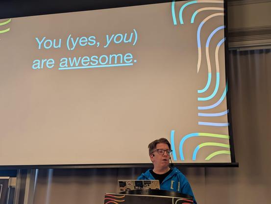 A photograph of Andy Piper opening Matrix Conference, with a slide reading "You (yes, you) are awesome."