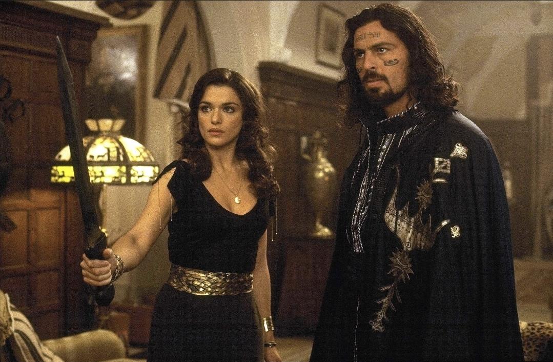 Oded Fehr and Rachel Weisz on The Mummy Returns. She is holding up a sword. He has face tattoos and a cape.