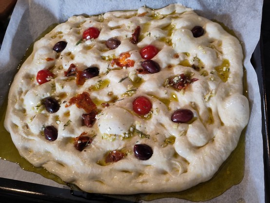 Pâte crie sur plaque avec olives, ails, tomatoes cerises, et huile d'olive.