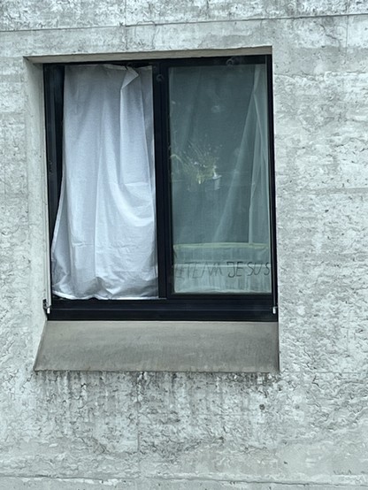 Ein Fenster. Von innen ist ein handgeschriebener Zettel befestigt, mit dem Text „#TEAMJESUS“. 