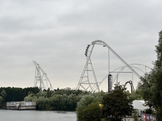 Das Bild zeigt im Vordergrund ein Fluss. Dahinter Sieht man Hyperia. Der Zug ist gerade am herunterrasen. Im Vordergrund ist auch noch Saw zu sehen, Bahn mit Senkrecht Lift und Drop. Sehr klein im vergleich zu Hyperia. 