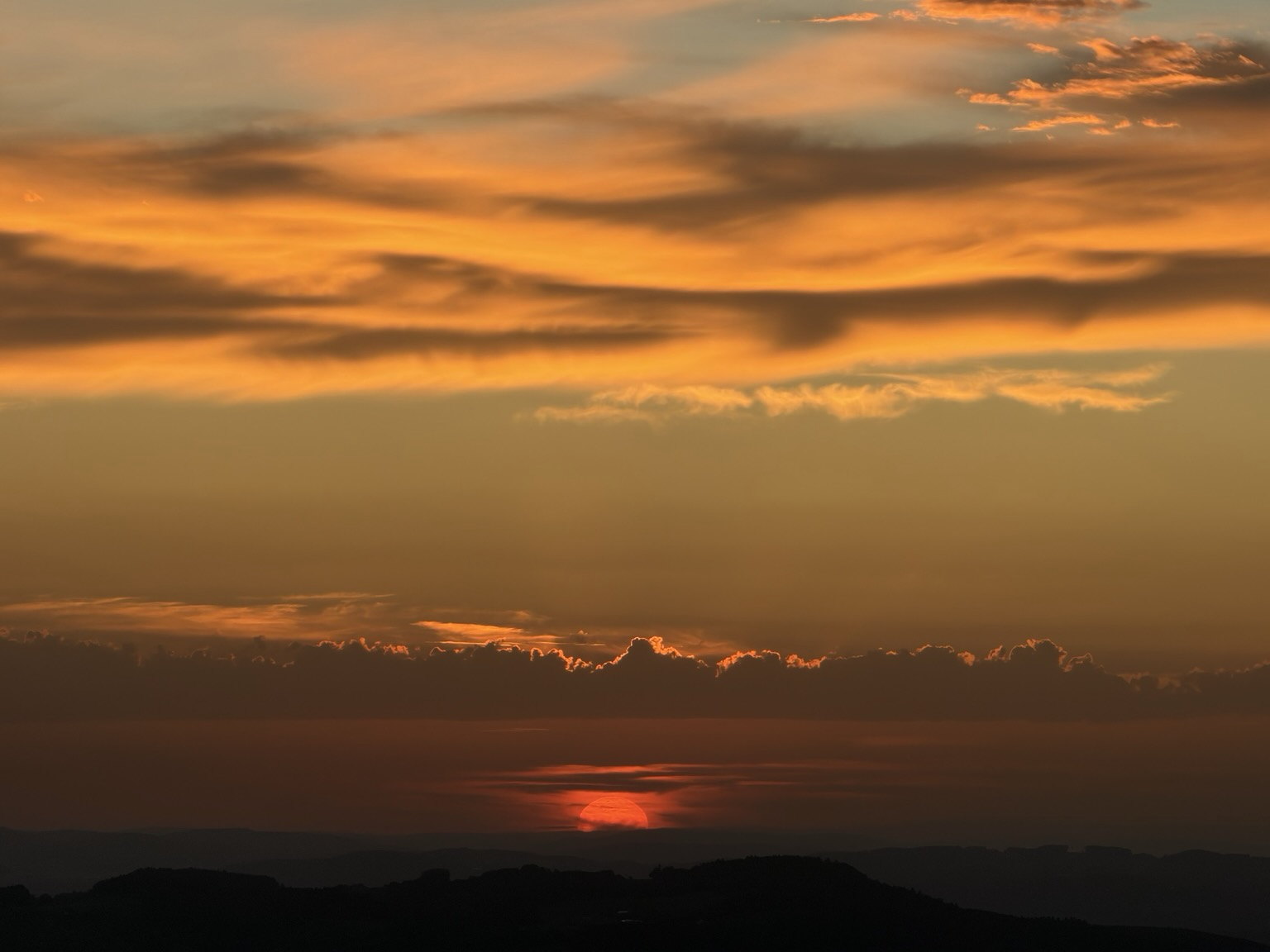 die untergehende sonne lässt die wolken golden leuchten