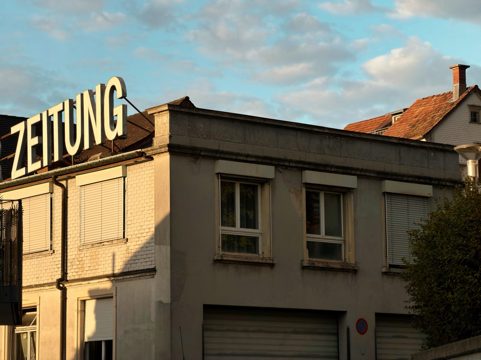 ein altes gebäude trägt den schriftzug „zeitung“. dieser wir von der abendsonne beleuchtet