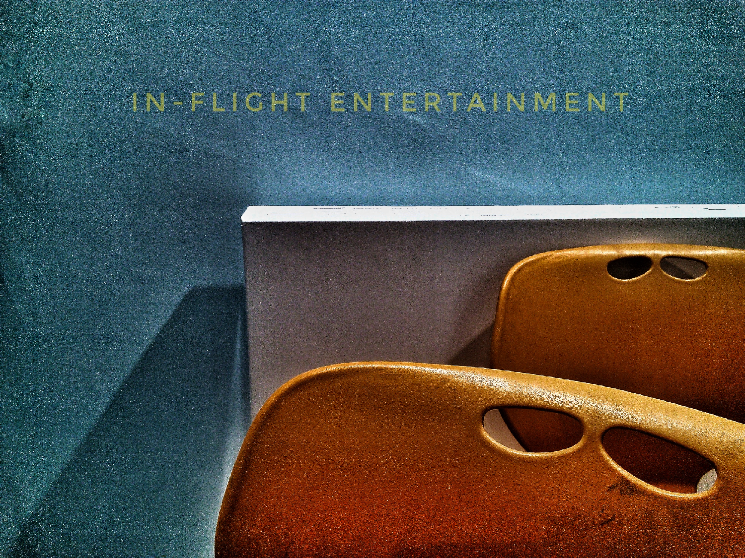 Two amber moulded forms with paired oval cutouts at the top sit, one in front of the other with a white rectangular fixture behind them. They all sit against a wall of teal, The image has a film grain to it. Olive lettering in the space above says: "IN-FLIGHT ENTERTAINMENT." The composition and caption conspire to make the mundane read as sparse, slightly clinical, retro-functional. it's more about the promise of entertainment in an inherently uncomfortable situation.