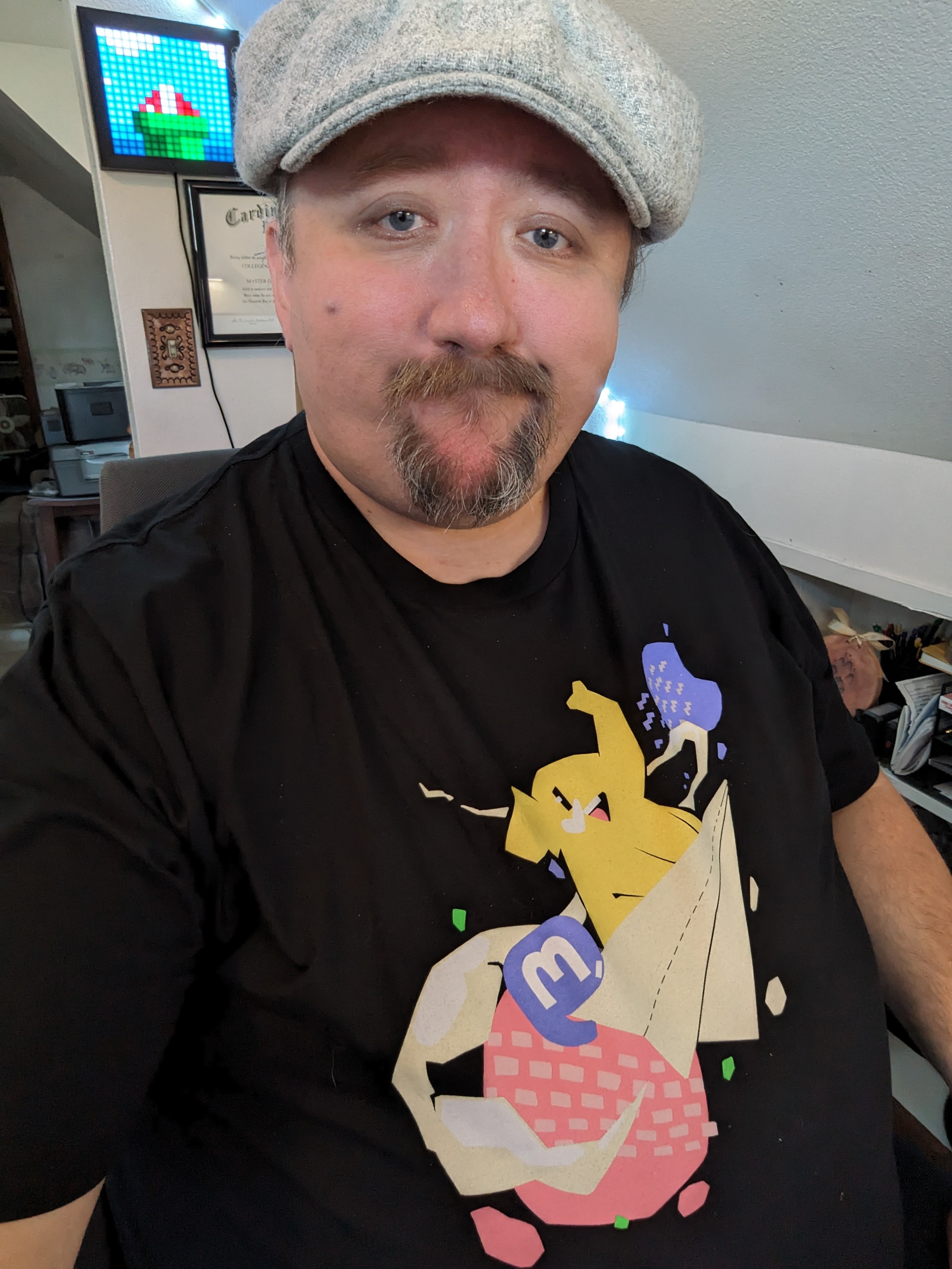 A goofy looking white dude wearing a flat cap and a black mastodon t-shirt.