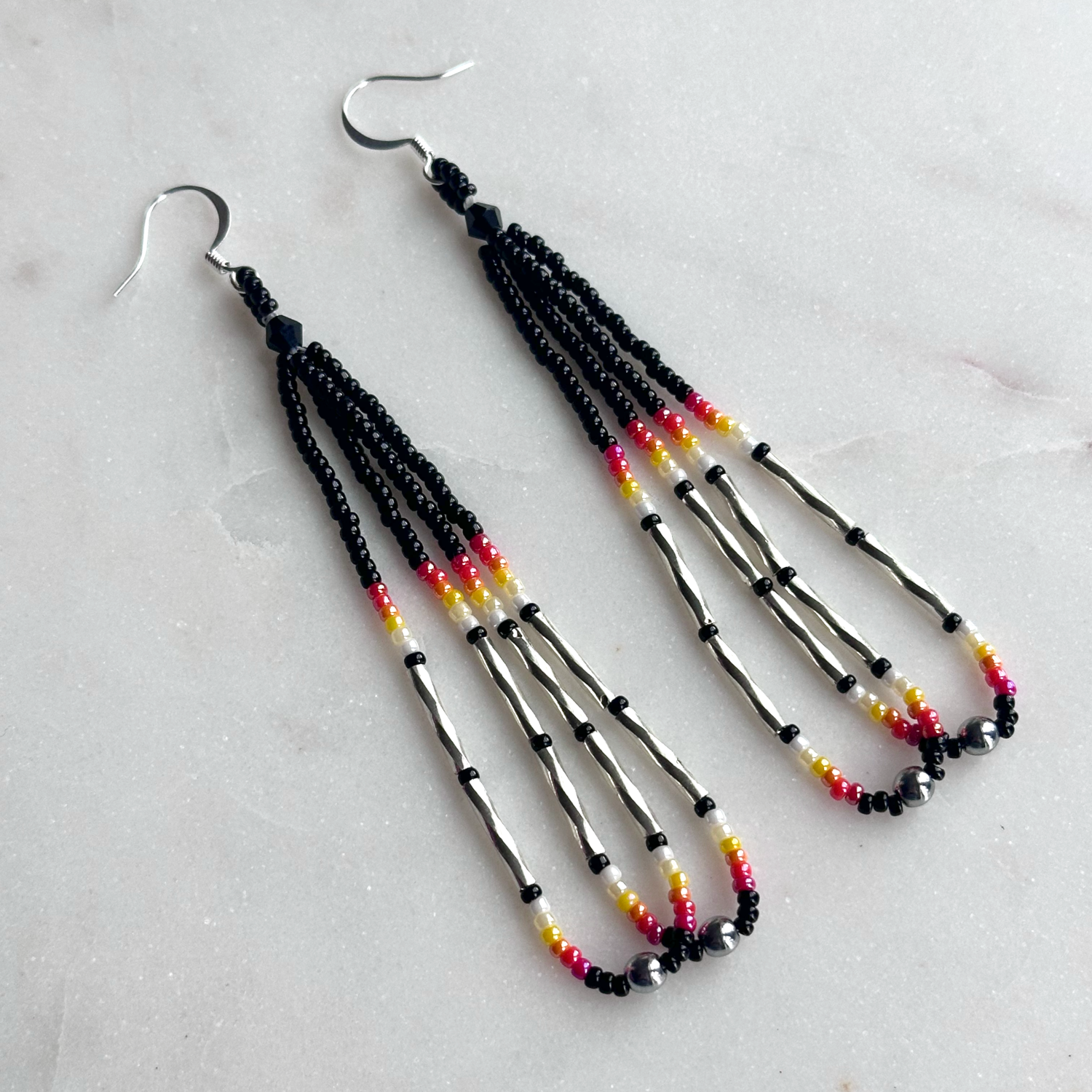 A pair of black beaded loop earrings with accents in red, orange, yellow, white, and silver