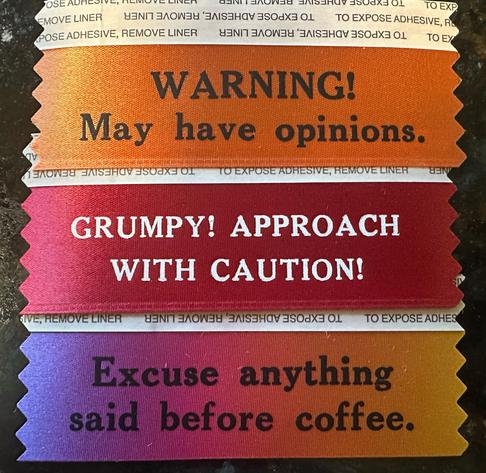Three badge ribbons. They say:

WARNING! May have opinions. 

GURMPY! APPROACH WITH CAUTION!

Excuse anything said before coffee. 