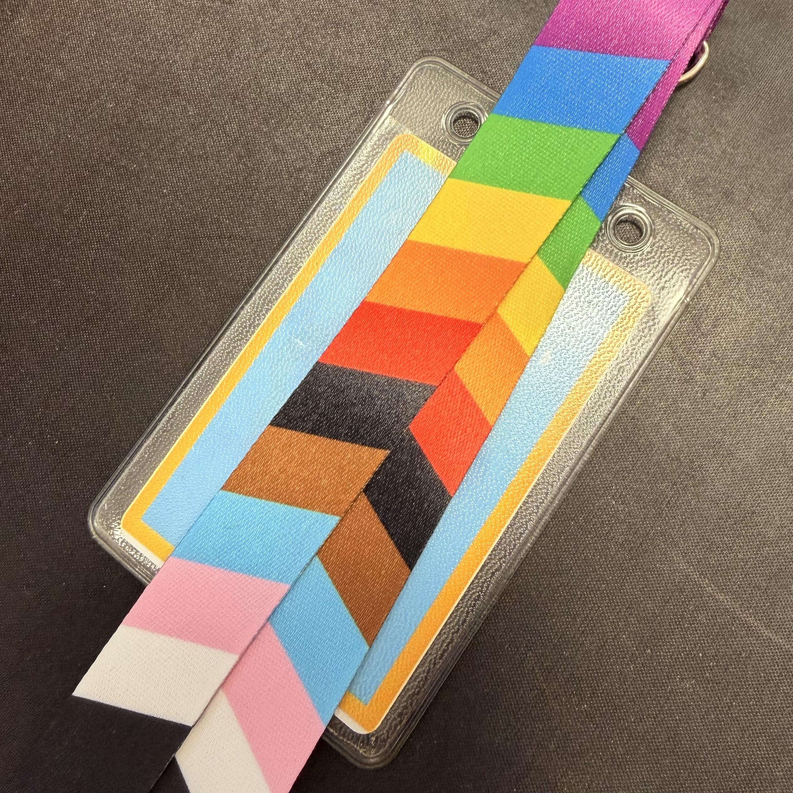 Pride themed lanyard laid atop an ID badge