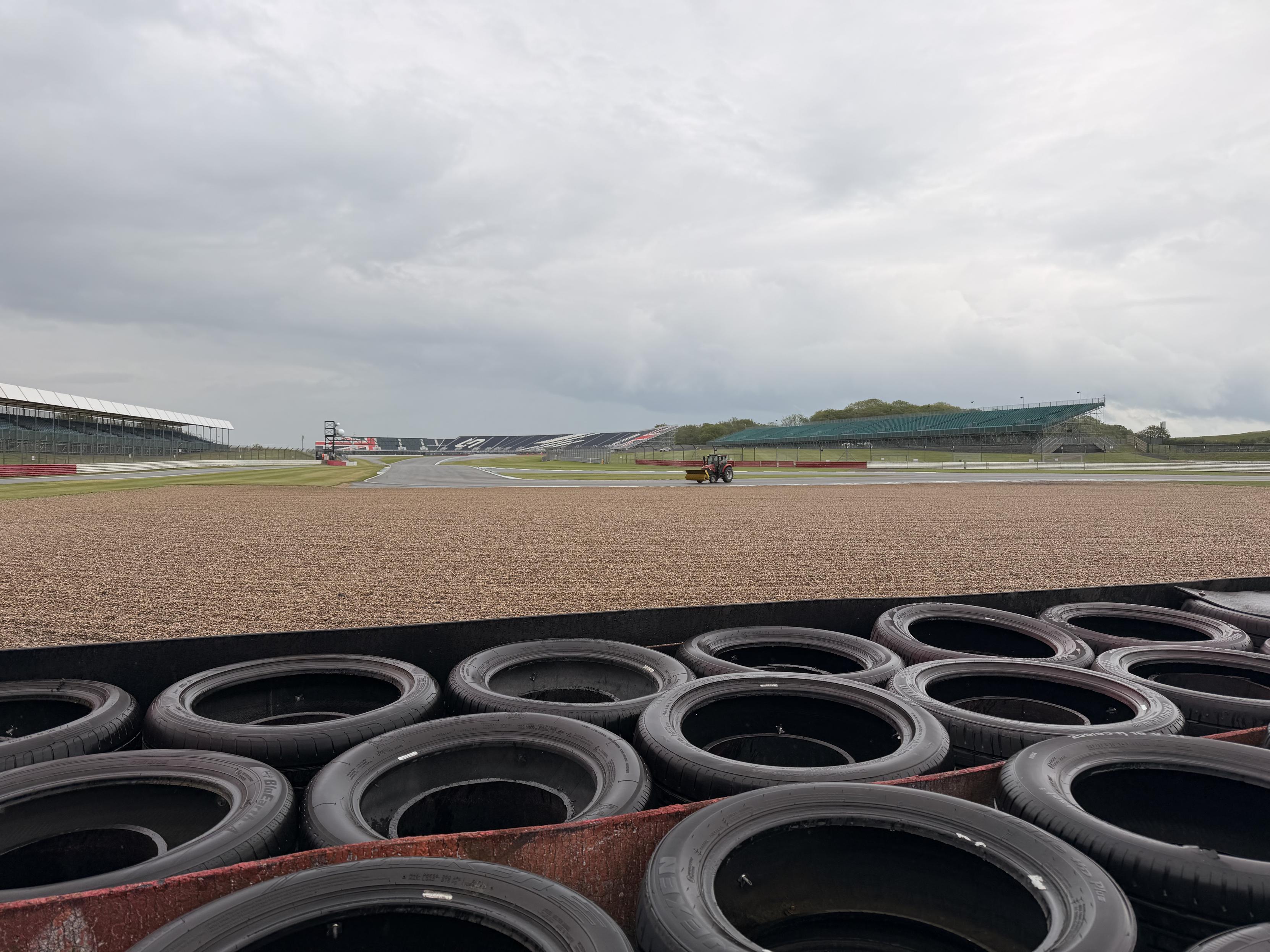 View from Vale marshal post looking up towards Stowe corner. Rain clouds hanging in the sky, a sweeper on track clearing gravel