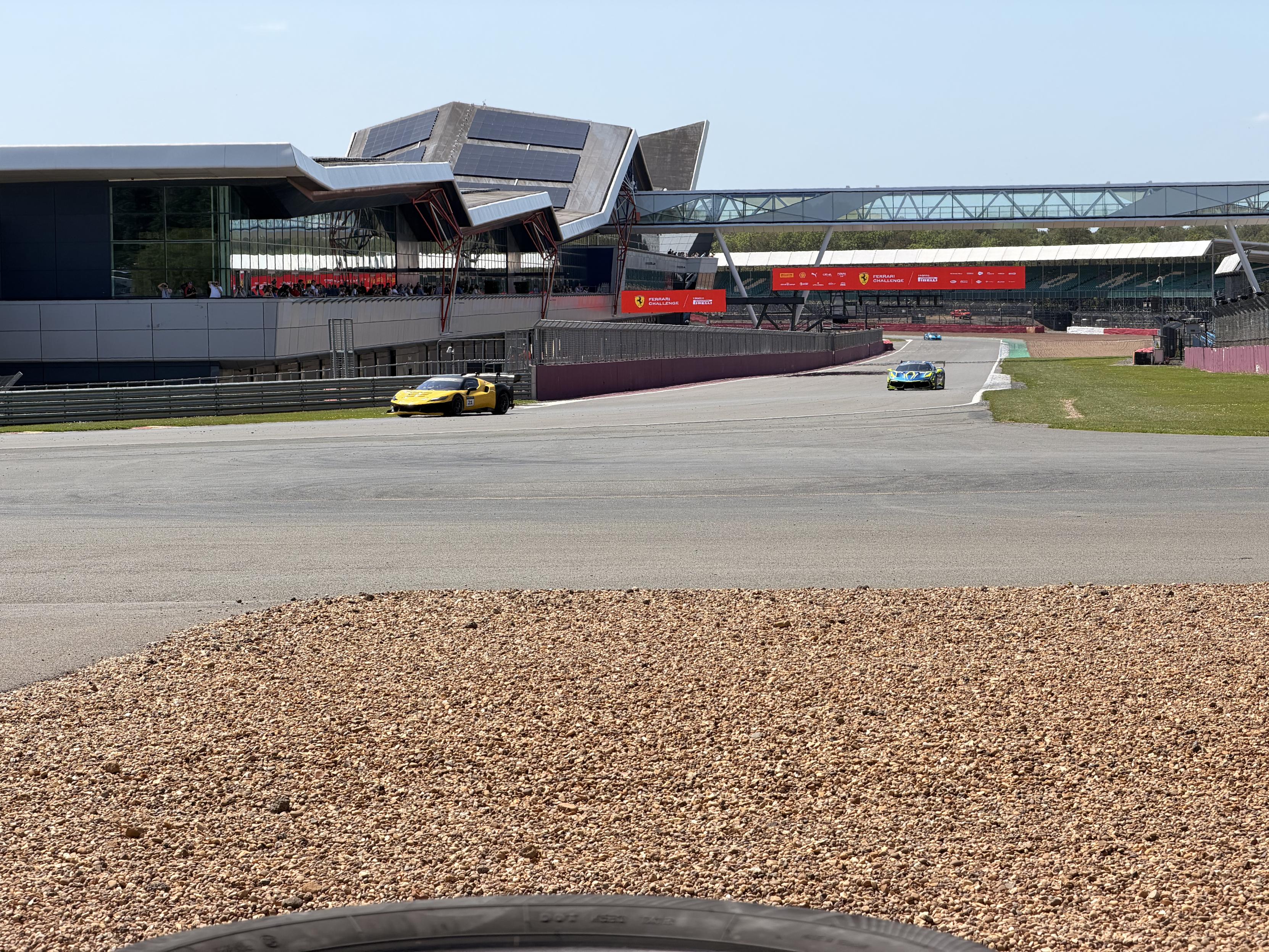 A view from Farm marshal post down the Hamilton straight, the Silverstone Wing on the left, two Ferrari race cars entering Abbey corner