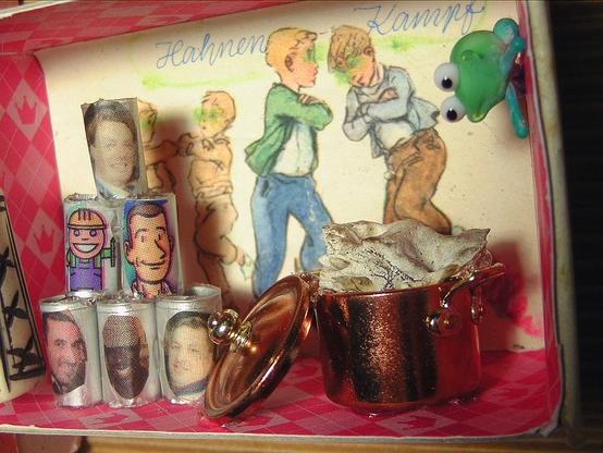 The opened box shows a miniature crime scene. The background is an oatmeal collector's picture from my childhood showing boys fighting with their arms crossed. Title: Cockfighting. In the foreground a pile of tin cans with portraits of men. At the top of the side wall a glass frog to kiss. Below a copper pot in which a piece of bone is boiling. What might be cooking there?