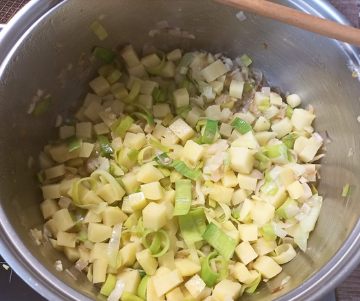 In einem Topf braten Schalotten, Knoblauch Kartoffeln und Porree