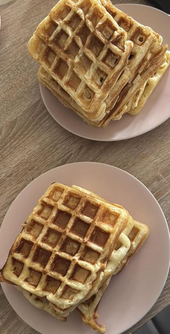 Ein Foto mit 2 Pinken Tellern auf einem Holztisch.
Auf den Tellern liegen selbst gebackene vegane Waffeln