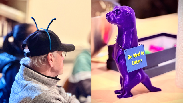 Das Foto ist eine Collage aus zwei Fotos. 

Linkes Foto: Eine weiße ältere cismännliche Person ist im Fokus. Er sitzt seitlich zur Kamera und schaut nach rechts. Er trägt eine dunkle Kappe und hat blaue 3D-gedruckte Ameisenantenne aufgesetzt. Der Hintergrund ist blurry. 

Rechtes Foto: Eine Otterfigur steht auf einem hellen Tisch. Der Otter ist lila und 3D-gedruckt. Um seinen Hals hängt ein blaues Schild mit gelber Schrift "Be kind to Otters".