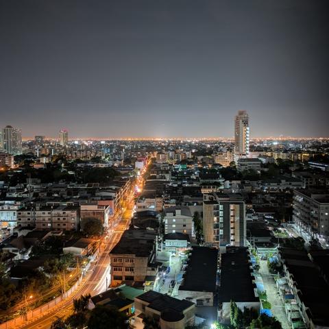Night view of city from high rise. Road glowing in orange with motion blur of vehicle passing by. Captured with Google Pixel from Bangkok Thailand