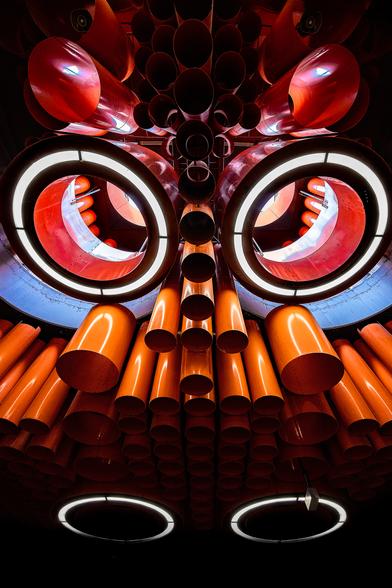Ceiling in Pannenhuis metro station in Brussels made of skylights and red and orange pipes. The picture framing shape an angry owl.