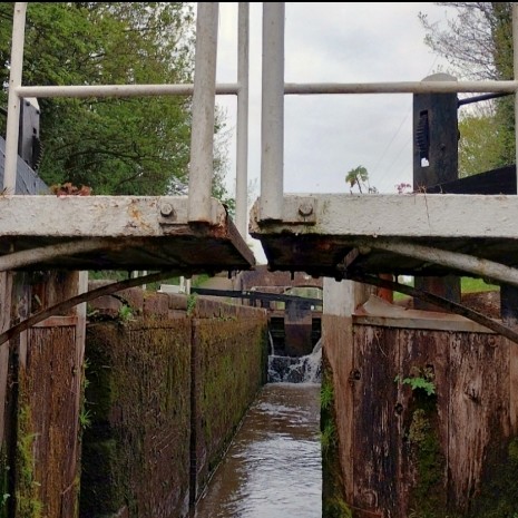 A footbridge over a lock, used by lock operators to get from the gate and paddles on one side pf the lock to the gate and paddles on the other side of the lock.

The bridge and its railing are painted on traditional British Waterways black and white.