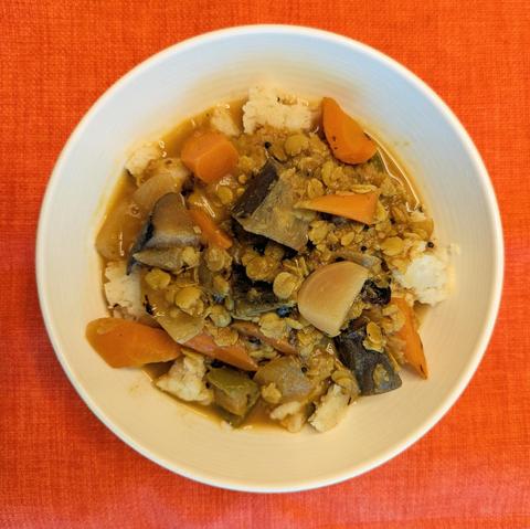 Bowl with uppuma with sambar with vegetables on top