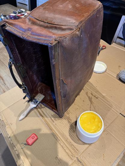 Old leather bag on a table, being coated with grease