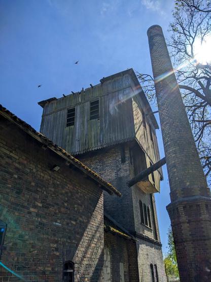 Opuszczone i zniszczone budynki z cegły. Rząd niskich zabudowań z dwuspadzistym dachem przechodzi w wyższą wieżę z górną częścią z drewna. Po prawej stoi jeszcze wyższy ceglany komin. Okna są powybijane lub zamurowane, dach na wieży ma spore ubytki.