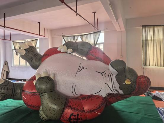 A giant inflatable sockeye salmon kaiju in brilliant spawning phase colors, tipped over on his side in a factory