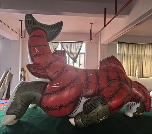 A giant inflatable sockeye salmon kaiju in brilliant spawning phase colors, tipped over on his front in a factory.  His snout is smooshed.