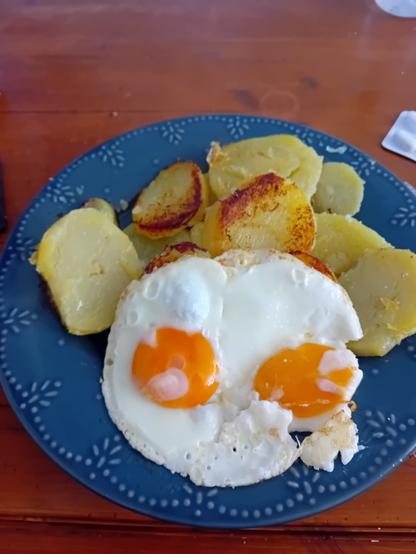 Pommes de terre et œufs sur le plat dans une assiette bleue