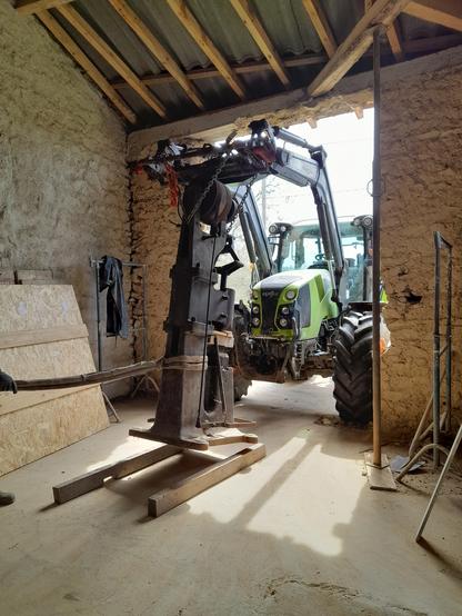 Marteau pilon déplacé par un tracteur a traver une ouverture dans un ancien bâtiment