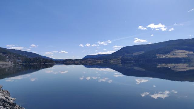 See in Norwegen bei Schönwetter. Himmel und Berge spiegeln sich (fast) symmetrisch im Wasser