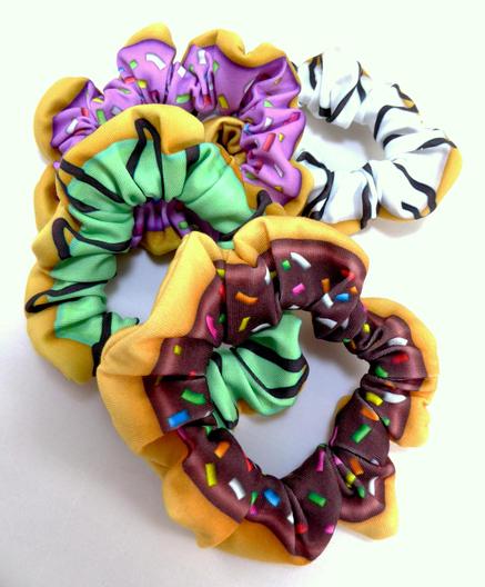 four donut scrunchies featuring chocolate sprinkle, mint chocolate drizzle, strawberry sprinkle, and marble drizzle